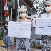 Bergaya bak pengantin mereka berpose di pinggir jalan sambil membawa karton seperti orang yang berdemo. Pak saya mau nikah!!! Bukan mau arisan! Jadi gak mungkin cuma 30 orang batasnya!! Kami tidak akan melanggar prokes! PPKM mohon jangan lagi diperpanjang. Terimakasih, demikian yang tertulis di karton yang dibawa oleh Nadya.Foto: Dok. Instagram @lutfiagizal.