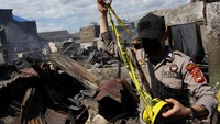 Anggota polisi memasang garis polisi di lokasi kebakaran di salah satu permukiman padat penduduk di Kecamatan Tamalate, Makassar, Sulawesi Selatan, Rabu (11/8/2021).