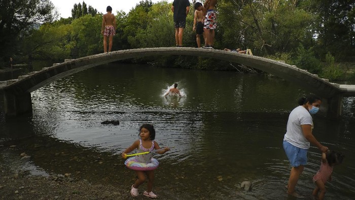 Cara Asik Warga Spanyol Mendinginkan Diri dari Cuaca Panas People cool off in water of the Arga River during a hot summer day in Pamplona, northern Spain, Wednesday, Aug. 11, 2021. (AP Photo/Alvaro Barrientos)
