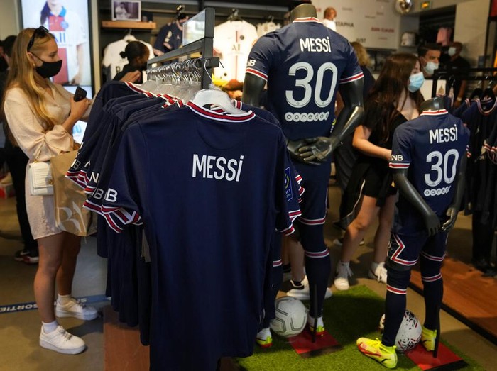 A Parsi Saint-Germain supporter shows a jersey bearing the name of Lionel Messi he just bought as Scarlett Su, right, from New York, smiles outside the official PSG shop, Wednesday, Aug. 11, 2021 in Paris. Lionel Messi is a 