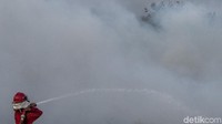 Petugas gabungan dari Manggala Agni Daops Banyuasin dan TNI menyemprotkan air agar api tidak merembet.