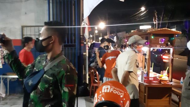 Muhammad Aslam, pedagang angkringan yang menggugat Presiden Jokowi soal perpanjangan PPKM (baju merah, bermasker hitam, berdiri di belakang gerobak).