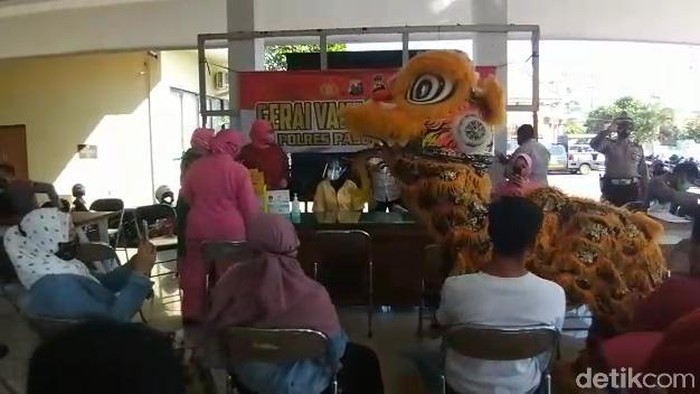 Warga yang mengikuti vaksinasi COVID-19 di Pendopo Kecamatan Panggungrejo, Kota Pasuruan dihibur barongsai. Atraksi kesenian ini mengusir penat warga yang tengah antre.