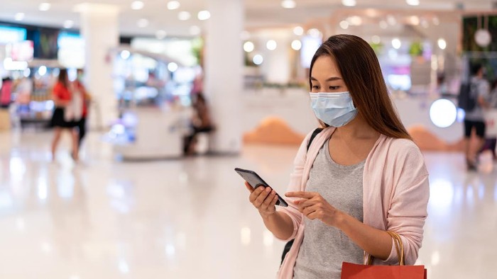 Young asian woman wearing surgical mask shopping in clothes store at the mall, New normal and lifestyle concept
