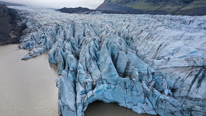 SVINAFELL, ICELAND - AUGUST 13: Melting ice from Svinafellsjokull glacier floats in a lake of meltwater as the glacier looms behind on August 13, 2021 near Svinafell, Iceland. Iceland is feeling a strong impact from global warming. Since the 1990s 90% of Iceland's glaciers have been retreating and projections for the future show a continued and strong reduction in size of its thee ice caps. Svinafellsjokull is one of dozens of glacier tongues that descend from Vatnajokull, Iceland's biggest ice cap.  (Photo by Sean Gallup/Getty Images)