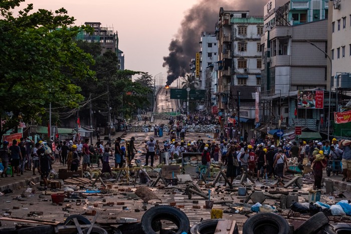 YANGON, MYANMAR - FEBRUARY 17: Protesters chant solgans and wave flags during an anti-coup protest at Sule Square on February 17, 2021 in downtown Yangon, Myanmar. Armored vehicles continued to be seen on the streets of Myanmars capital, but protesters turned out despite the military presence. The military junta that staged a coup against the elected National League for Democracy (NLD) government moved to keep the countrys de-facto leader Aung San Suu Kyi under house arrest after she was charged with violations of import-export and Covid prevention laws. (Photo by Hkun Lat/Getty Images)