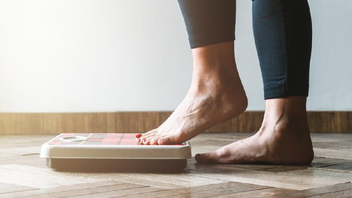 diet Female checking kilogrammes getting on the scale - self care and body positivity concept - warm flare on left