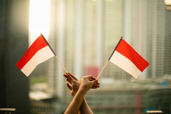 Ilustrasi Hari Kemerdekaan cropped hand of person holding Indonesia Flag in the city scape