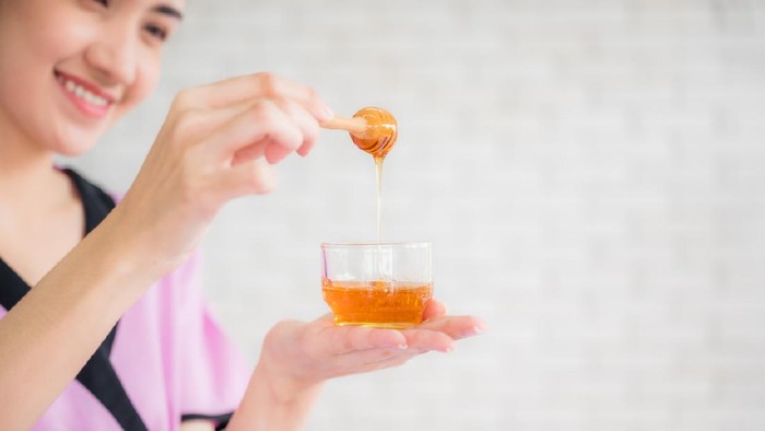 Beautiful asian young woman professional masseuse holding honey cup for spa body treatment in spa salon. Female masseuse prepared pure honey for facial mask. Beauty treatment and healthcare concept.