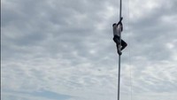 Foto: Joni memanjat tiang bendera untuk memperbaiki pengait yang bermasalah saat upacara HUT ke-73 RI. (Screenshot video viral)