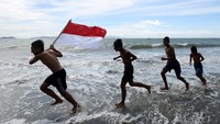 Anak-anak bermain sambil membawa bendera merah putih di pantai wisata Gampong Jawa, Banda Aceh, Aceh, Minggu (15/8/2021). Pantai Gampong Jawa yang berhadapan langsung dengan pulau Weh dan perairan Laut Selat Malaka telah menjadi destinasi wisata baru yang ramai dikunjungi wisatawan lokal terutama pada sore hari dan akhir pekan. ANTARA FOTO/Irwansyah Putra  