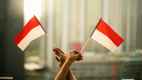 cropped hand of person holding Indonesia Flag in the city scape