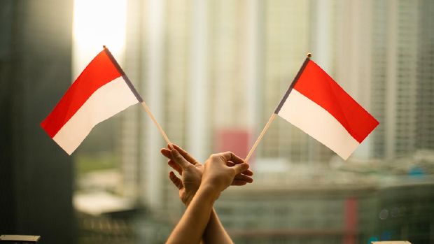 cropped hand of person holding Indonesia Flag in the city scape