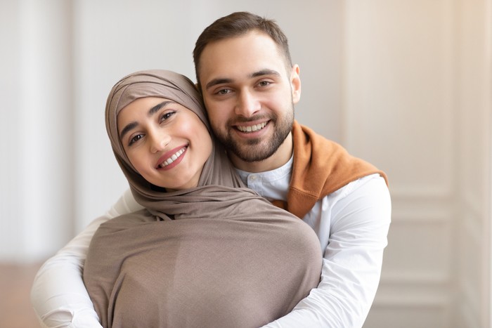 pasangan muslim Awaiting Baby. Joyful Muslim Couple Holding Positive Pregnancy Test Sitting Together On Sofa Indoors, Focus On Test. Happy Parents-To-Be, Childbirth Concept. Shallow Depth, Cropped