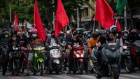Para pengunjuk rasa mengendarai sepeda motor sambil membawa bendera selama demonstrasi anti-pemerintah di sepanjang jalan utama pada 15 Agustus 2021 di Bangkok, Thailand. Sirachai Arunrugstichai/Getty Images  