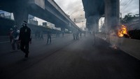 Kelompok yang umumnya terdiri dari anak-anak muda itu melempari garis polisi yang menghalangi jalan mereka dengan batu, kembang api dan bahan peledak kecil yang dikenal sebagai “bom pingpong.” Sirachai Arunrugstichai/Getty Images.