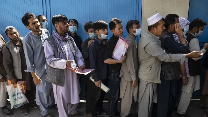 Orang-orang Afghanistan duduk di dinding saat orang-orang menunggu berjam-jam untuk menarik uang. Para pejabat mengatakan pejuang Taliban telah memasuki Kabul dan mencari penyerahan tanpa syarat dari pemerintah pusat.