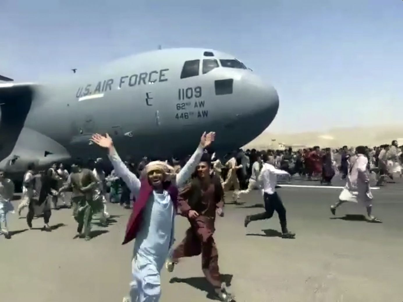 Hundreds of people run alongside a U.S. Air Force C-17 transport plane as it moves down a runway of the international airport, in Kabul, Afghanistan, Monday, Aug.16. 2021. Thousands of Afghans have rushed onto the tarmac at the airport, some so desperate to escape the Taliban capture of their country that they held onto the American military jet as it took off and plunged to death. (Verified UGC via AP)