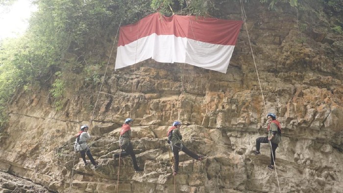 Empat mahasiswa Aceh mengibarkan bendera Merah Putih di tebing