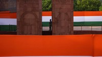 Petugas keamanan melintas di tengah bendera kebangsaan India, menjelang hari kemerdekaan negara itu (13/8). India menjadi koloni Inggris sebelum merdeka. Saat ini, India menganut sistem federal dengan 28 negara bagian dan 6 wilayah otonom. (AP Photo/Manish Swarup)