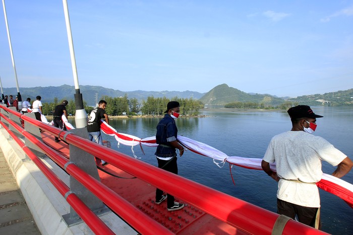 PEMASANGAN BENDERA MERAH PUTIH DI JEMBATAN YOUTEFA Nelayan melintasi Jembatan Youtefa yang dipasang bendera Merah Putih di Jayapura, Papua, Selasa (17/8/2021). Pemasangan bendera Merah Putih sepanjang 400 meter tersebut guna memeriahkan HUT ke-76 RI. ANTARA FOTO/Gusti Tanati/wpa/aww.