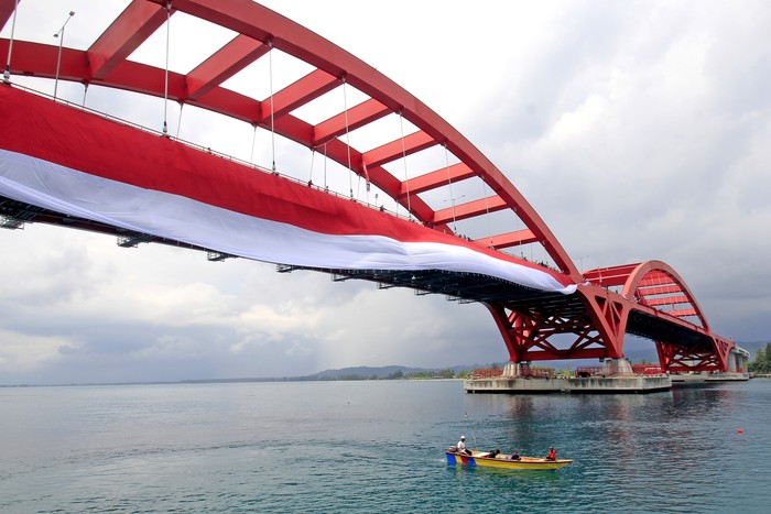 PEMASANGAN BENDERA MERAH PUTIH DI JEMBATAN YOUTEFA Nelayan melintasi Jembatan Youtefa yang dipasang bendera Merah Putih di Jayapura, Papua, Selasa (17/8/2021). Pemasangan bendera Merah Putih sepanjang 400 meter tersebut guna memeriahkan HUT ke-76 RI. ANTARA FOTO/Gusti Tanati/wpa/aww.