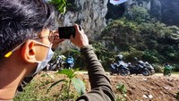 Seorang warga memotret bendera merah putih raksasa yang membentang di Tebing Hawu, di Kampung Cidadap, Desa Padalarang, Kecamatan Padalarang, Kabupaten Bandung Barat (KBB), Selasa (17/8/2021).