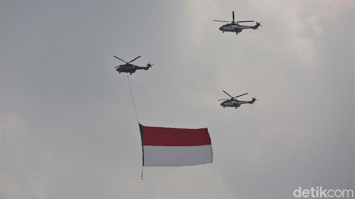 Bendera Merah Putih berukuran raksasa menghiasi langit Jakarta. Bendera itu dibawa oleh pesawat tempur dan helikopter di tengah perayaan HUT ke-76 RI.