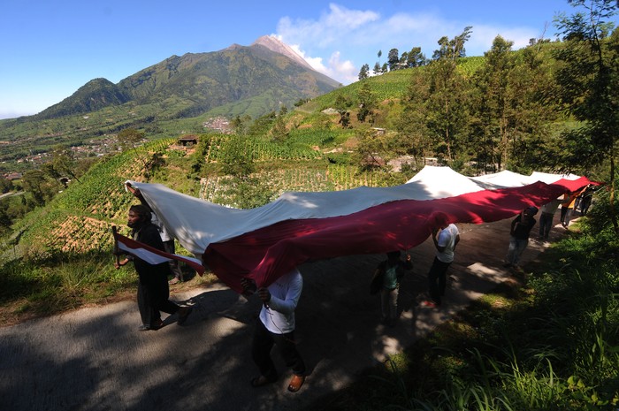 WARGA KAKI GUNUNG MERBABU PERINGATI HUT KEMERDEKAAN INDONESIA Sejumlah warga membentangkan bendera merah putih dengan berlatar belakang Gunung Merapi di lahan pertanian kaki Gunung Merbabu, Selo Tengah, Selo, Boyolali, Jawa Tengah, Selasa (17/8/2021). Kegiatan yang diikuti warga setempat itu untuk memperingati HUT Kemerdekaan ke-76 Republik Indonesia serta menanamkan jiwa nasionalisme kepada generasi muda. ANTARA FOTO/Aloysius Jarot Nugroho/wsj.