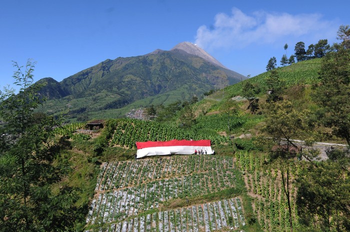 WARGA KAKI GUNUNG MERBABU PERINGATI HUT KEMERDEKAAN INDONESIA Sejumlah warga membentangkan bendera merah putih dengan berlatar belakang Gunung Merapi di lahan pertanian kaki Gunung Merbabu, Selo Tengah, Selo, Boyolali, Jawa Tengah, Selasa (17/8/2021). Kegiatan yang diikuti warga setempat itu untuk memperingati HUT Kemerdekaan ke-76 Republik Indonesia serta menanamkan jiwa nasionalisme kepada generasi muda. ANTARA FOTO/Aloysius Jarot Nugroho/wsj.