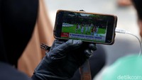 Meski tak ada perayaan secara langsung di depan istana, warga yang datang dan berkunjung di Plaza Monas, Jalan Merdeka Selatan, Selasa (17/8/2021) tetap asyik menikmati upacara pengibaran bendera di Istana Negara secara daring.