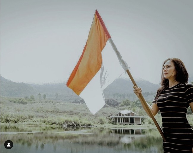 Wulan Guritno tak lupa merayakan HUT ke-76 RI di sela-sela liburannya di Garut. Wulan berpose di tepi danau sambil memegang bendera merah putih. Foto: Instagram