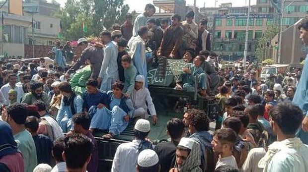 Taliban fighters and local residents sit on an Afghan National Army (ANA) Humvee vehicle along the roadside in Laghman province on August 15, 2021. (Photo by - / AFP)