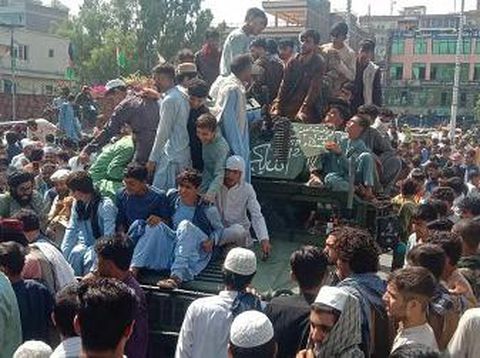 Taliban fighters and local residents sit on an Afghan National Army (ANA) Humvee vehicle along the roadside in Laghman province on August 15, 2021. (Photo by - / AFP)