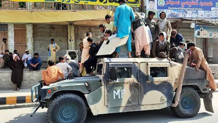 Taliban fighters and local residents sit on an Afghan National Army (ANA) Humvee vehicle along the roadside in Laghman province on August 15, 2021. (Photo by - / AFP)