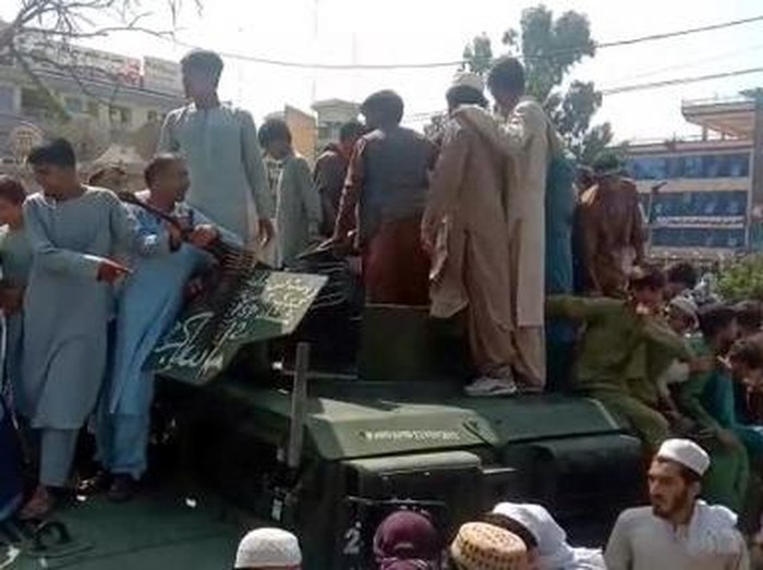Taliban fighters and local residents sit on an Afghan National Army (ANA) Humvee vehicle along the roadside in Laghman province on August 15, 2021. (Photo by - / AFP)