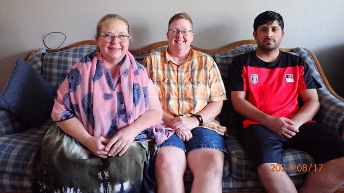 In this photo provided by Caroline Clarin, is Sheril Raymond, from left, Clarin and Ihsanullah Patan sitting together in an apartment on Tuesday, Aug. 17, 2021, in Fergus Falls, Minn. Raymond and Clarin, who worked for a U.S. Department of Agriculture in Afghanistan, helped Patan and his family arrive to the United States and get settled in Minnesota. They are part of a number of Americans trying to help Afghans fleeing their country. (Caroline Clarin via AP)