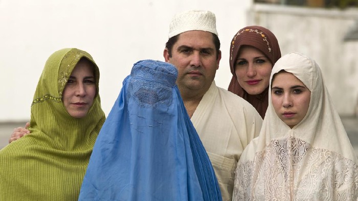 Bamyian city, Bamyian Province, Afghanistan - November 14, 2010: Four Afghan women in blue and black burqa walking on dirt path in barren land