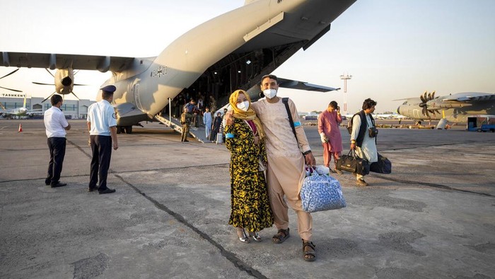 People evacuated from Afghanistan pose in front of a German Bundeswehr airplane after arriving at the airport in Tashkent, Uzbekistan, Tuesday, Aug. 17, 2021. The federal armed forces evacuates German citizens and local Afghan forces from Kabul. (AP Photo/Bundeswehr via AP)
