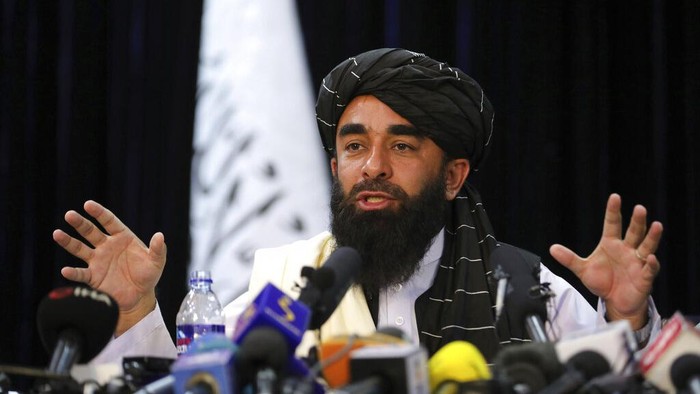In front of a Taliban flag, Taliban spokesman Zabihullah Mujahid speaks at at his first news conference, in Kabul, Afghanistan, Tuesday, Aug. 17, 2021. For years, Mujahid had been a shadowy figure issuing statements on behalf of the militants. Mujahid vowed Tuesday that the Taliban would respect womens rights, forgive those who resisted them and ensure a secure Afghanistan as part of a publicity blitz aimed at convincing world powers and a fearful population that they have changed. (AP Photo/Rahmat Gul)