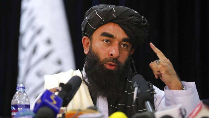 In front of a Taliban flag, Taliban spokesman Zabihullah Mujahid speaks at at his first news conference, in Kabul, Afghanistan, Tuesday, Aug. 17, 2021. For years, Mujahid had been a shadowy figure issuing statements on behalf of the militants. Mujahid vowed Tuesday that the Taliban would respect womens rights, forgive those who resisted them and ensure a secure Afghanistan as part of a publicity blitz aimed at convincing world powers and a fearful population that they have changed. (AP Photo/Rahmat Gul)