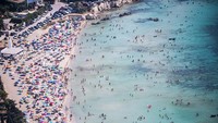 Wisatawan memadati pantai Fontane Bianche dalam pemandangan udara dari helikopter Penjaga Pantai di Siracusa, Italia.  