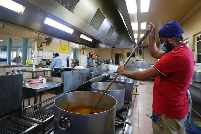 SYDNEY, AUSTRALIA - AUGUST 19: Volunteer cooks prepare large volumes of chapati to be packed into meal kits for those in need at the Gurdwara Sahib Glenwood Sikh Temple on August 19, 2021 in Sydney, Australia. The Australian Sikh Association (ASA) serves Sydney's Gurdwara Sahib Glenwood - the largest Sikh congregation in Australia. The Gurdwara Sahib at Glenwood is the hub of religious and community activities all year round with members of the Sikh community visiting the Gurdwara Sahib to pray, meditate and listen to the teachings and hymns from Guru Granth Sahib. During Sydney's COVID-19 lockdown, the ASA has started a daily tiffin service, distributing cooked takeaway food at the main gate providing around 500 meals per day to people in need. For those community members who can't come to temple, ASA volunteers are delivering food, medicines and other supplies to people affected by lockdown restrictions. The Australian Sikh Association has also been active in the community encouraging people to get vaccinated for COVID-19, hosting a vaccination pop up clinic at the Gurdwara Sahib in Glenwood. (Photo by Lisa Maree Williams/Getty Images)