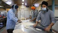 Asisten koki Gurjee Singh menyiapkan shahi paneer dalam jumlah besar untuk dikemas ke dalam peralatan makan bagi mereka yang membutuhkan di Kuil Gurdwara Sahib Glenwood Sikh di Sydney, Australia, (19/8).