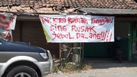 Spanduk bernada protes jalan rusak itu terpasang di pagar-pagar di pinggir jalan, gapura jalan, dinding dan sejumlah kios depan bekas pasar sapi Nogosari yang sudah tidak dipakai.