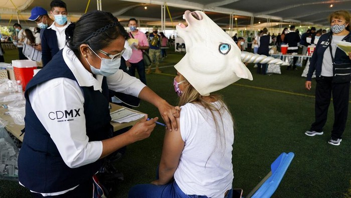 A young man, wearing a costume, flashes a V sign, as he waits in line to be vaccinated with a dose of the Pfizer COVID-19, during a vaccination drive for people between the ages of 18-29, in Mexico City, Thursday, Aug. 19, 2021. The capital’s south side borough of Xochimilco is encouraging young residents to dress up in costumes and compete for prizes if they come for their first COVID-19 vaccine dose. (AP Photo/Eduardo Verdugo)