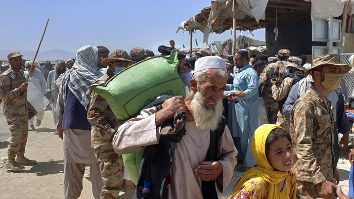 Pakistan Afghanistan Pakistani soldiers stand guard while stranded people walk towards the Afghan side at a border crossing point, in Chaman, Pakistan, Friday, Aug. 13, 2021. Pakistan opened its Chaman border crossing for people who had been stranded in recent weeks. Juma Khan, the Pakistan border towns deputy commissioner, said the crossing was reopened following talks with the Taliban. (AP Photo/Jafar Khan)