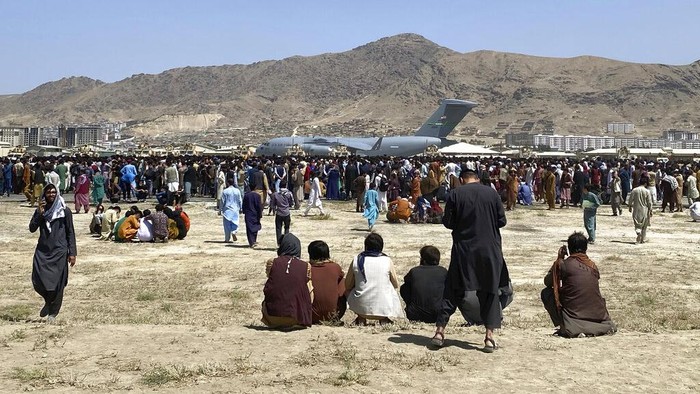 Pakistani soldiers stand guard while stranded people walk towards the Afghan side at a border crossing point, in Chaman, Pakistan, Friday, Aug. 13, 2021. Pakistan opened its Chaman border crossing for people who had been stranded in recent weeks. Juma Khan, the Pakistan border towns deputy commissioner, said the crossing was reopened following talks with the Taliban. (AP Photo/Jafar Khan)