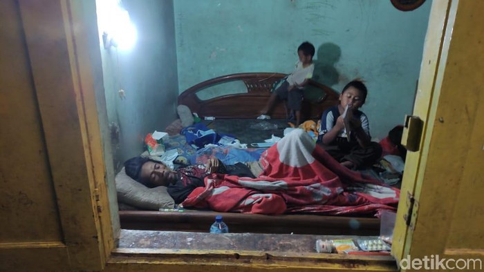 Potret mengarukan tampak dari jendela sebuah rumah di Kota Malang. Tampak dua bocah tengah merawat sang ayah yang terbaring lumpuh.