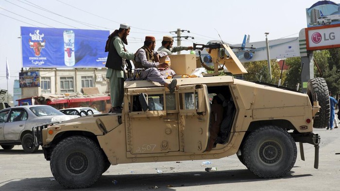 Taliban fighters patrol as two Traffic policemen stand, left, in Kabul, Afghanistan, Thursday, Aug. 19, 2021. The Taliban celebrated Afghanistans Independence Day on Thursday by declaring they beat the United States, but challenges to their rule ranging from running a country severely short on cash and bureaucrats to potentially facing an armed opposition began to emerge. (AP Photo/Rahmat Gul)